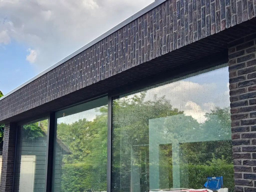 Gevelrenovatie en voegwerk bij moderne woning met donkere gevelsteen en grote ramen