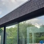 Gevelrenovatie en voegwerk bij moderne woning met donkere gevelsteen en grote ramen