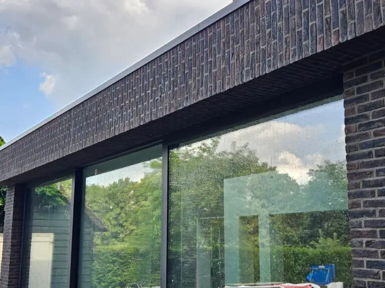 Gevelrenovatie en voegwerk bij moderne woning met donkere gevelsteen en grote ramen